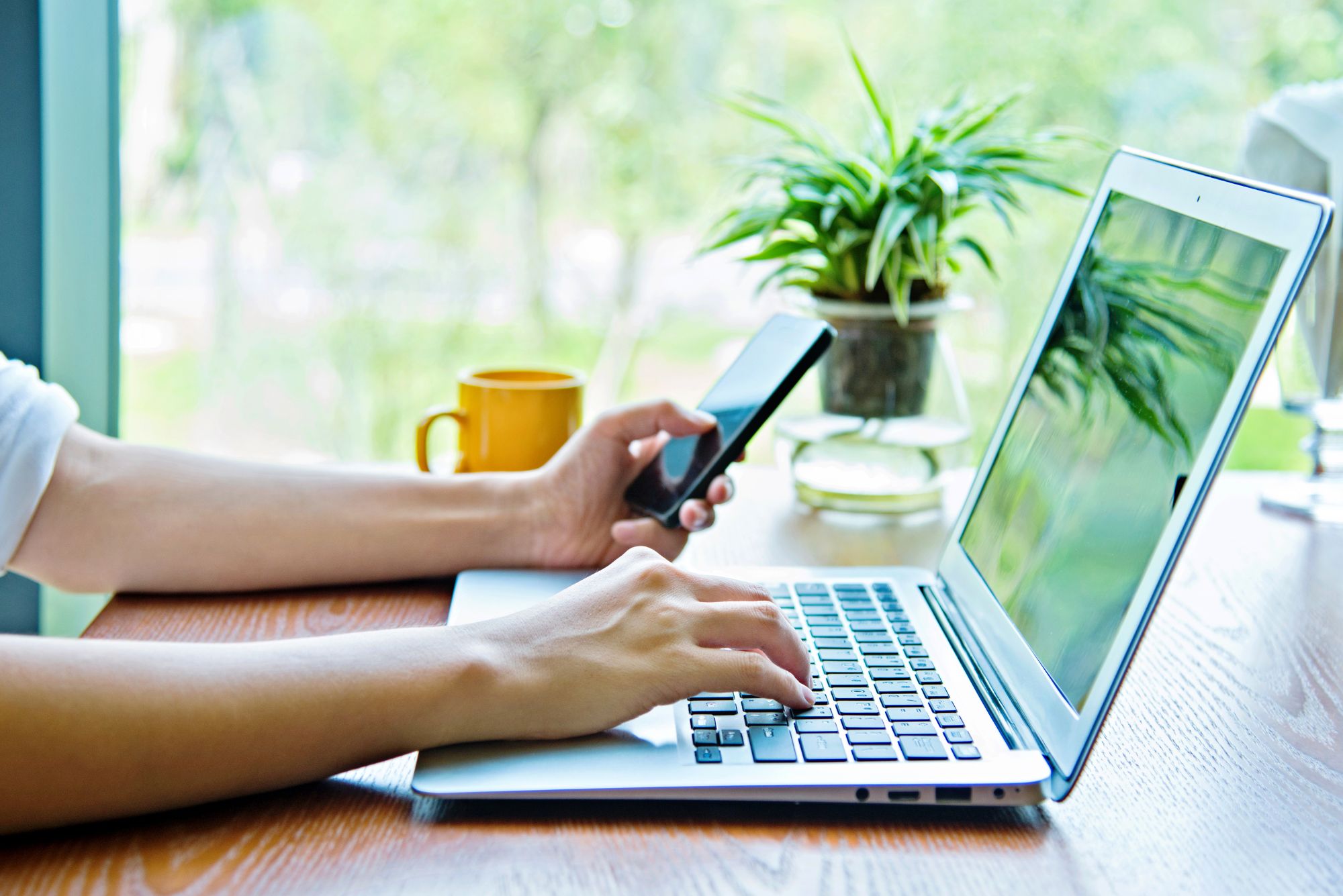 A woman sitting down using her laptop to fill out online patient intake forms.