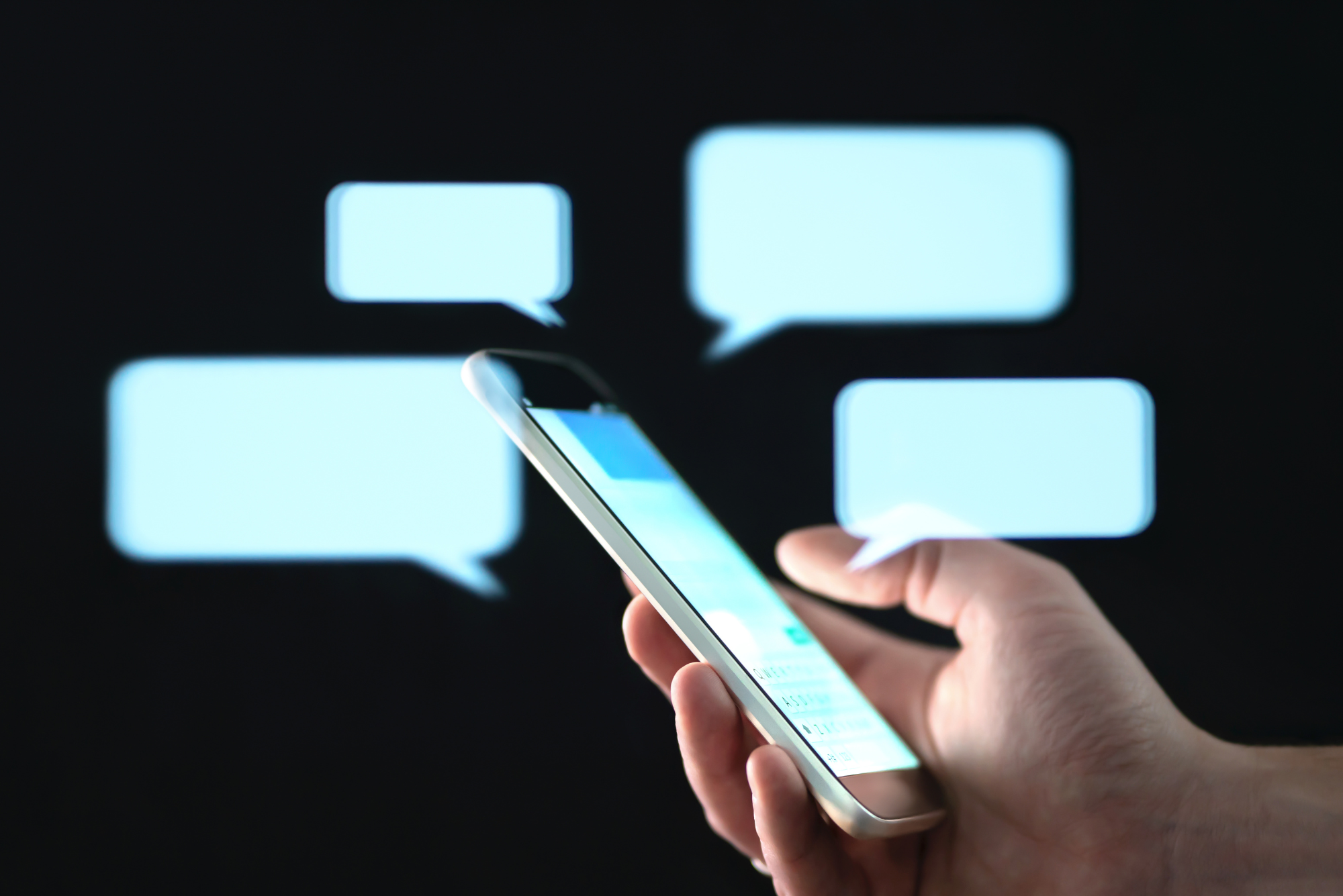 A person holds a phone in their hand with text message bubbles around it symbolizing the importance of patient outreach.