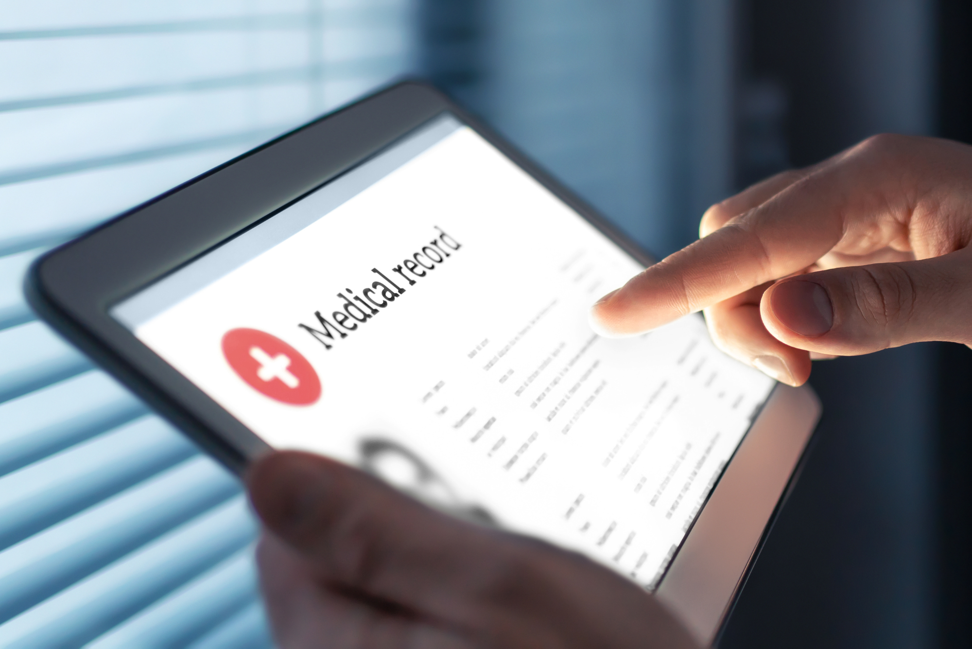 A patient scrolls through their electronic health records on an iPad next to the window.