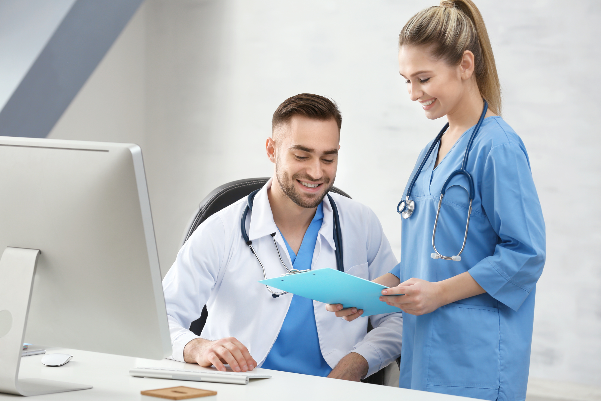 Two doctors stand together in front of computer using the new referral management software offered by Simple Interact.