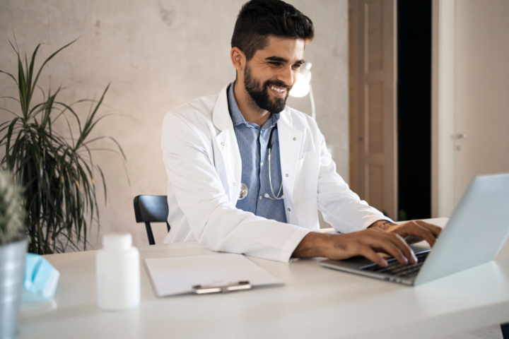 A doctor sits at a desk, easily closing a referral patient with Simple Interact’s software.